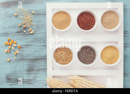 Vari tipi di grani in ciotole ( la quinoa,amaranto, miglio, chia,grano saraceno ) con riso, ceci e il mais accanto a bocce Foto Stock