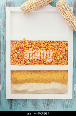 Il mais. Due le pannocchie di granoturco a fianco di farina di mais e kernel su sfondo rustico. Vista dall'alto, dai toni vintage immagine, lo spazio vuoto Foto Stock