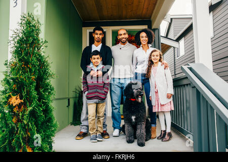 Famiglia e cane sorridente sul patio Foto Stock