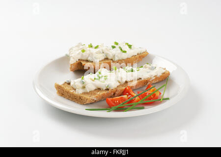 Aprire di fronte sandwich con erba cipollina diffusione su piastra bianca Foto Stock