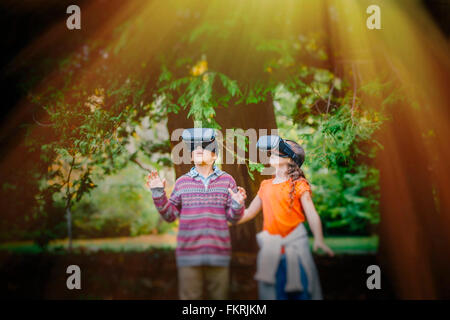 Razza mista bambini utilizzando la realtà virtuale occhiale all'aperto Foto Stock