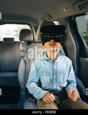 Razza mista boy utilizzando la realtà virtuale gli occhiali di protezione in auto Foto Stock