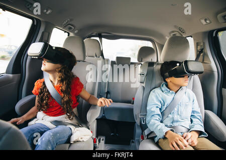 Razza mista bambini utilizzando la realtà virtuale gli occhiali di protezione in auto Foto Stock