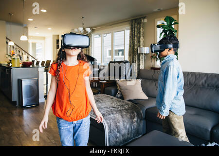 Razza mista bambini utilizzando la realtà virtuale gli occhiali di protezione in salotto Foto Stock