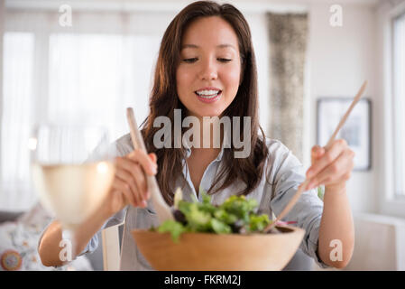 Razza mista donna tossing salad Foto Stock