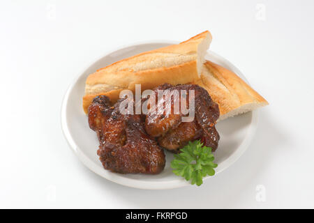 Piatto di arrosto di ali e baguette fresca su sfondo bianco Foto Stock