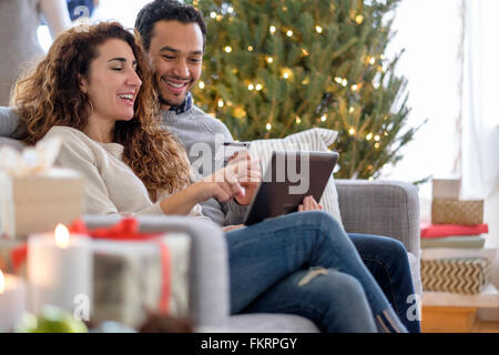 Giovane shopping con tavoletta digitale sul divano Foto Stock