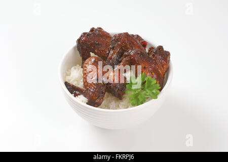 Ciotola di arrosto di ali di pollo con riso su sfondo bianco Foto Stock