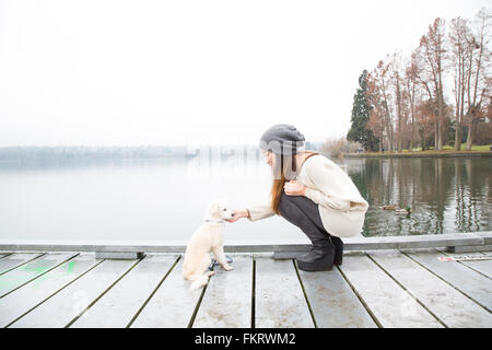 Donna Giapponese petting cane vicino al lago Foto Stock