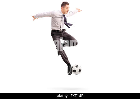 Studio shot del giovane imprenditore giocando a calcio girato a mezz aria isolata su sfondo bianco Foto Stock