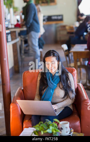 Donna ispanica utilizzando laptop in cafe Foto Stock