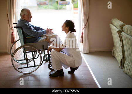 L'infermiera di parlare al paziente in sedia a rotelle Foto Stock