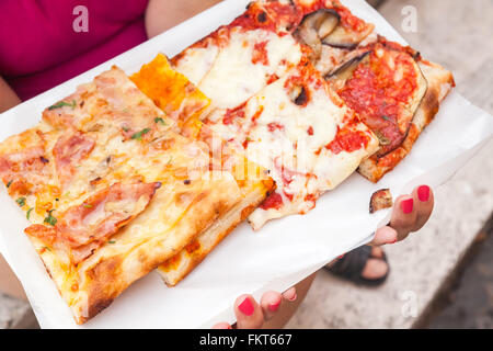 Fette di carni diverse pizza italiana nelle mani della donna Foto Stock