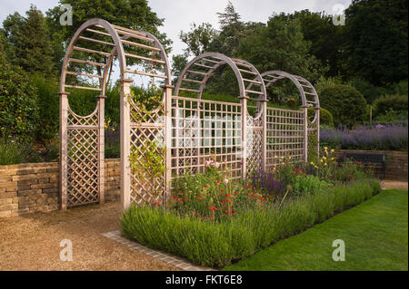 Tunnel arbour e piante erbacee confine in bella, progettato e paesaggistici, tradizionale giardino, Burley in Wharfedale, West Yorkshire, Inghilterra - in estate. Foto Stock