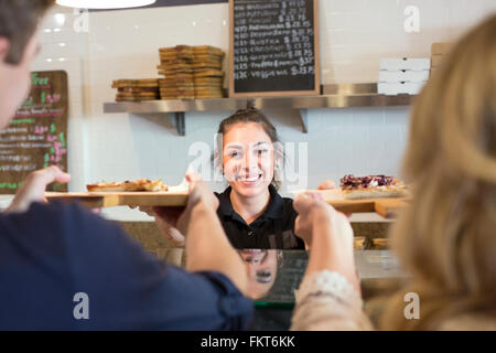 Server di consegnare la pizza ai clienti in cafe Foto Stock