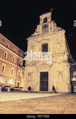 La facciata della chiesa con orologio da parete e vecchio vecchio case durante la notte, Gaeta, Italia. Vintage correzione tonale foto filtro, vecchio stile di effetto Foto Stock