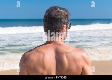 Uomo maturo guardando oceano, vista posteriore, Ipanema, Rio de Janeiro, Brasile Foto Stock