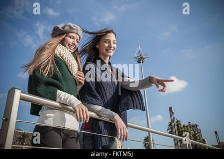 Basso angolo di visione delle giovani donne appoggiata contro la ringhiera che guarda lontano di puntamento e sorridente Foto Stock