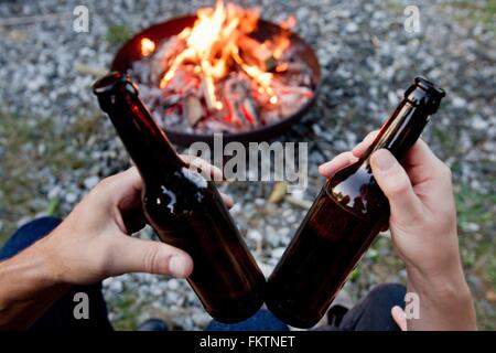 Mani tenendo le bottiglie di birra con il fuoco Foto Stock