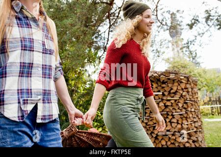 Due donne che portano cesto le mele in giardino Foto Stock