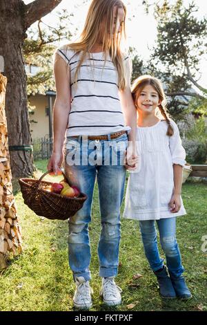 Madre e figlia Holding Hands, madre cestello di contenimento mele Foto Stock