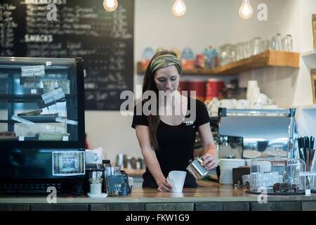 Femmina giovane cameriera di preparare caffè al contatore Foto Stock