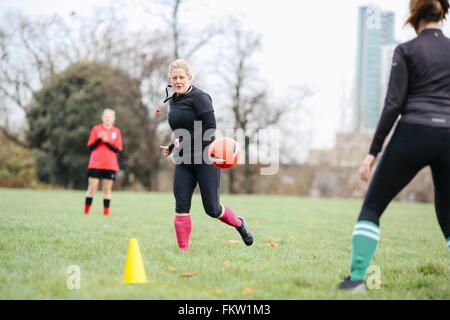 Femmina di giocatori di calcio avente la pratica del calcio in posizione di parcheggio Foto Stock