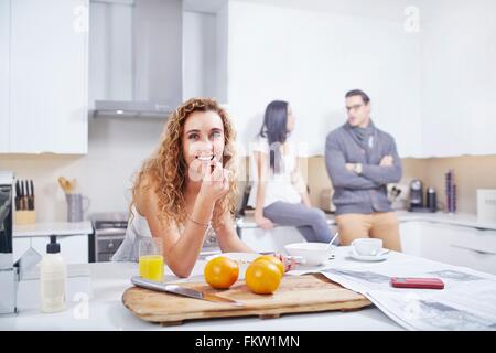 Ritratto di giovane donna di mangiare cereali per la colazione al banco di cucina Foto Stock