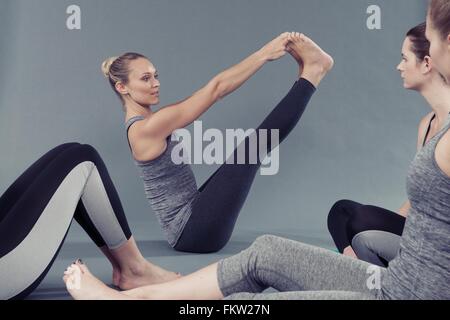 Giovani donne facendo esercizio di stretching e sfondo grigio Foto Stock