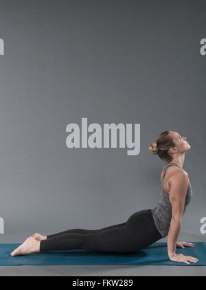 Giovane donna a praticare yoga e sfondo grigio Foto Stock