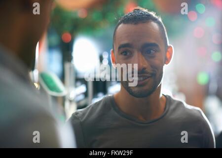 Giovane uomo in public house guarda lontano sorridente Foto Stock