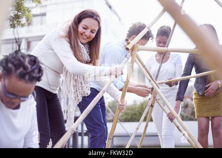 I colleghi di team building edificio attività struttura in legno sorridente Foto Stock