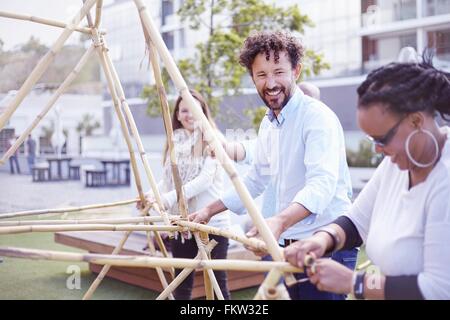 I colleghi di team building edificio attività struttura in legno sorridente Foto Stock