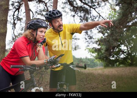 Mountain bike paio utilizzando la navigazione dello smartphone in foresta Foto Stock