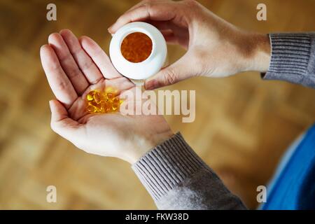 Giovane donna prendendo farmaci da bottiglia, close-up Foto Stock