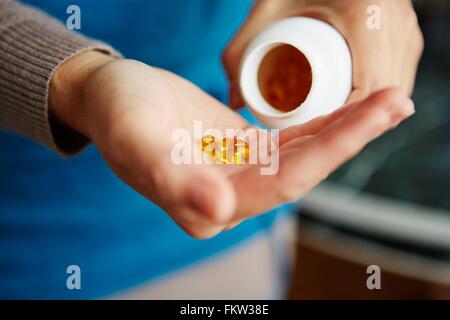 Giovane donna prendendo farmaci da bottiglia, close-up Foto Stock