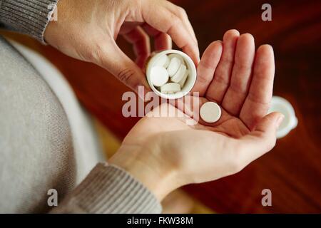 Giovane donna prendendo farmaci da vasca, close-up Foto Stock