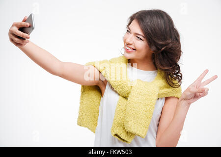 Sorridente giovane donna rendendo selfie foto sullo smartphone isolato su uno sfondo bianco Foto Stock
