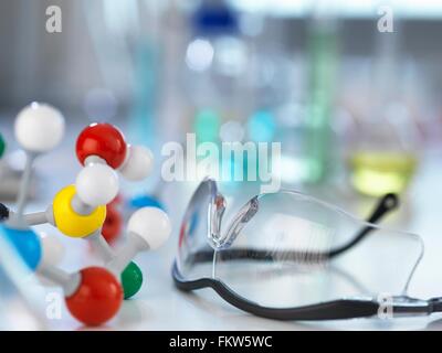 Occhiali di sicurezza e modello molecolare sul banco da laboratorio Foto Stock