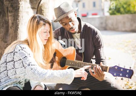 Paio di imparare a suonare la chitarra in posizione di parcheggio Foto Stock