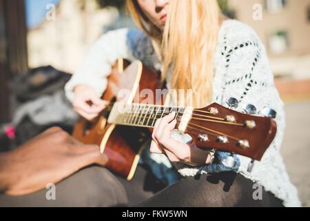 La donna a suonare la chitarra Foto Stock