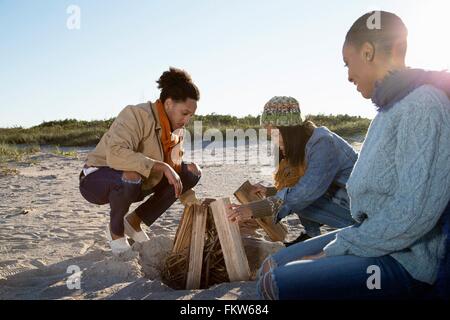 Tre amici sulla spiaggia, la preparazione di fuoco di campo Foto Stock