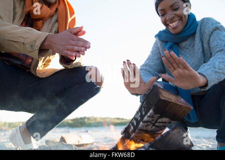 Amici riscaldando le mani sul fuoco di campo Foto Stock