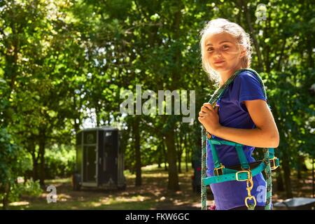 Vista laterale della ragazza cavallo portante redini sulla spalla guardare fotocamera a sorridere Foto Stock