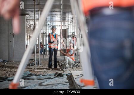 Maschio e femmina costruttori prendendo le misure per geometra Foto Stock