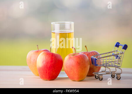Mele e succo di mela con un carrello su una tavola di legno, per esterno Foto Stock