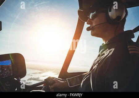 Close up di un pilota di volare a bordo di un elicottero con sun flare entrando nel pozzetto. Foto Stock