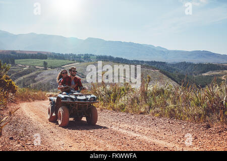 Giovane uomo e donna con divertimento durante la guida di una moto quad. Coppia giovane godendo fuoristrada di cavalcare un giorno d'estate. Foto Stock