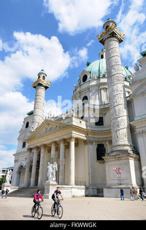 Due ciclisti ride davanti alla Karlskirche (San Carlo, la chiesa), Karlplatz, Vienna, Austria Foto Stock