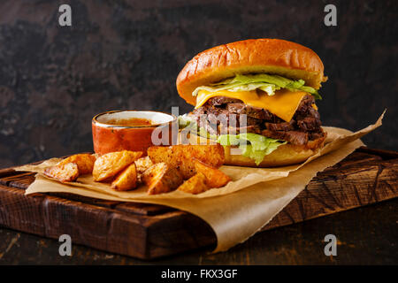 Pastrami Burger con fette di arrosto di manzo e le patate e cunei su sfondo scuro Foto Stock